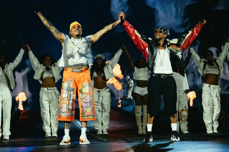 Chris Brown and Usher raising hands together on stage
