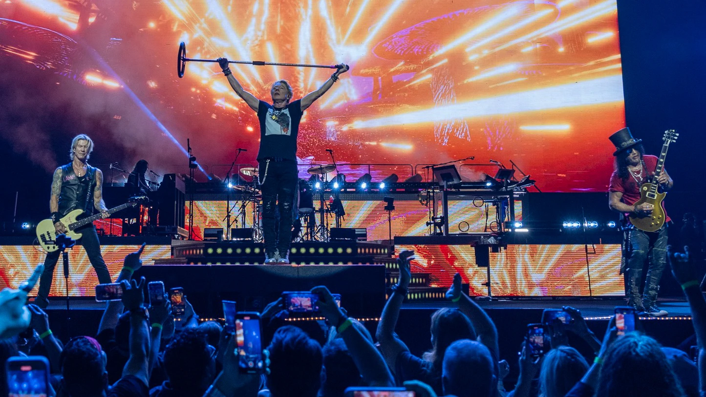 Axl Rose raising a mic stand overhead on stage